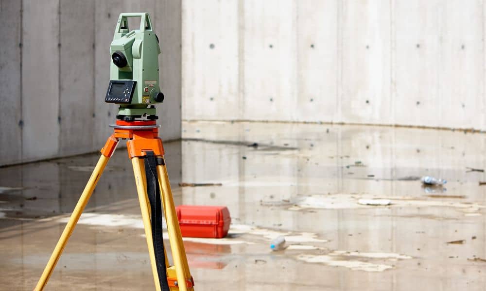 Flood elevation certificate surveyor equipment - ALTA SURVEY Nevada Total station surveying equipment set up on wet concrete after heavy rain, illustrating flood elevation measurement and drainage assessment.
