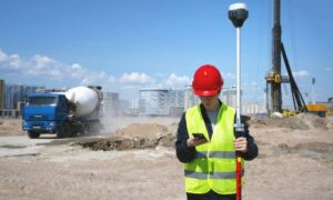 Surveyor using GPS equipment on a construction site performing a construction survey to verify field layout and accuracy during earthworks