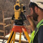 Surveyor performing elevation survey with total station equipment on a construction site in North Las Vegas for watershed management project

