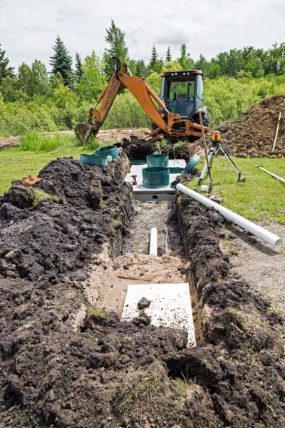 Excavator digging and septic system installation in progress after a failed percolation test on land.
