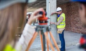 Construction survey in progress with a surveyor using a theodolite to mark precise points on a building site for accurate construction planning.