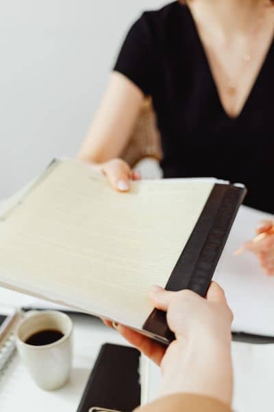 Person handing over signed property documents during a mortgage closing survey
