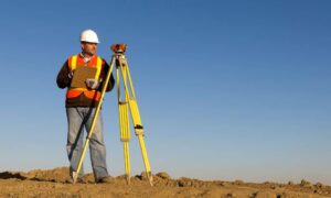 A land surveyor performing an ALTA Land Title Survey inspection after a small earthquake in a dry landscape