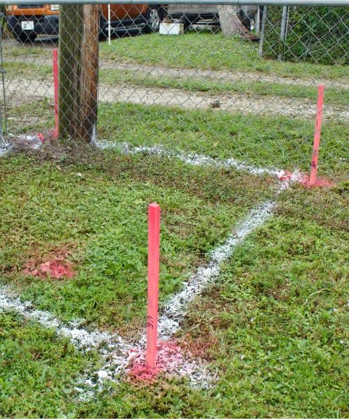 Marked property corner stakes and painted lines showing how a boundary survey defines the exact area before any construction work begins