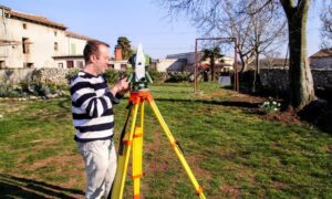 A land surveyor using a total station to measure a residential property during a property survey