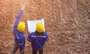 Surveyors reviewing site plans on undeveloped land before a perc test is scheduled