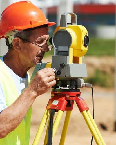 Licensed land surveyor collecting field data with a total station, showing how a topographic survey provides accurate information for planning and construction