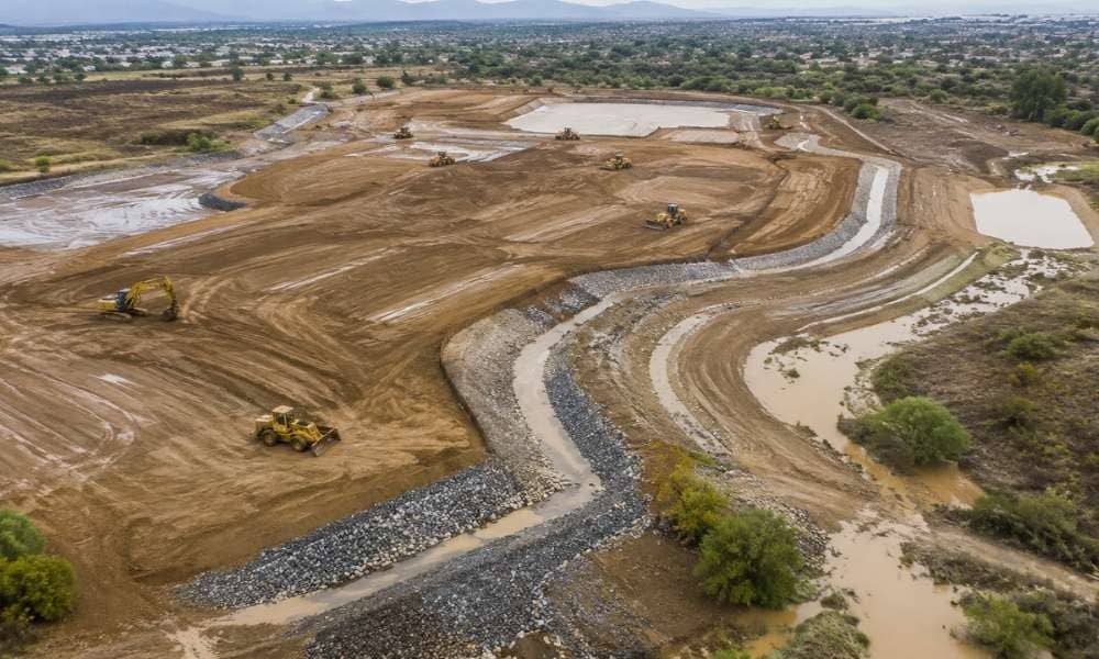 Aerial view of a graded construction site with drainage channels and earthwork showing how a topographic survey supports site grading for changing rainfall patterns
